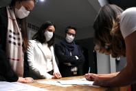 equipe da defensoria em pé atras da mesa, ppl assinando documento