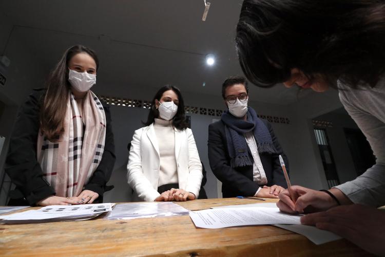 equipe da defensoria em pé atras da mesa, ppl assinando documento